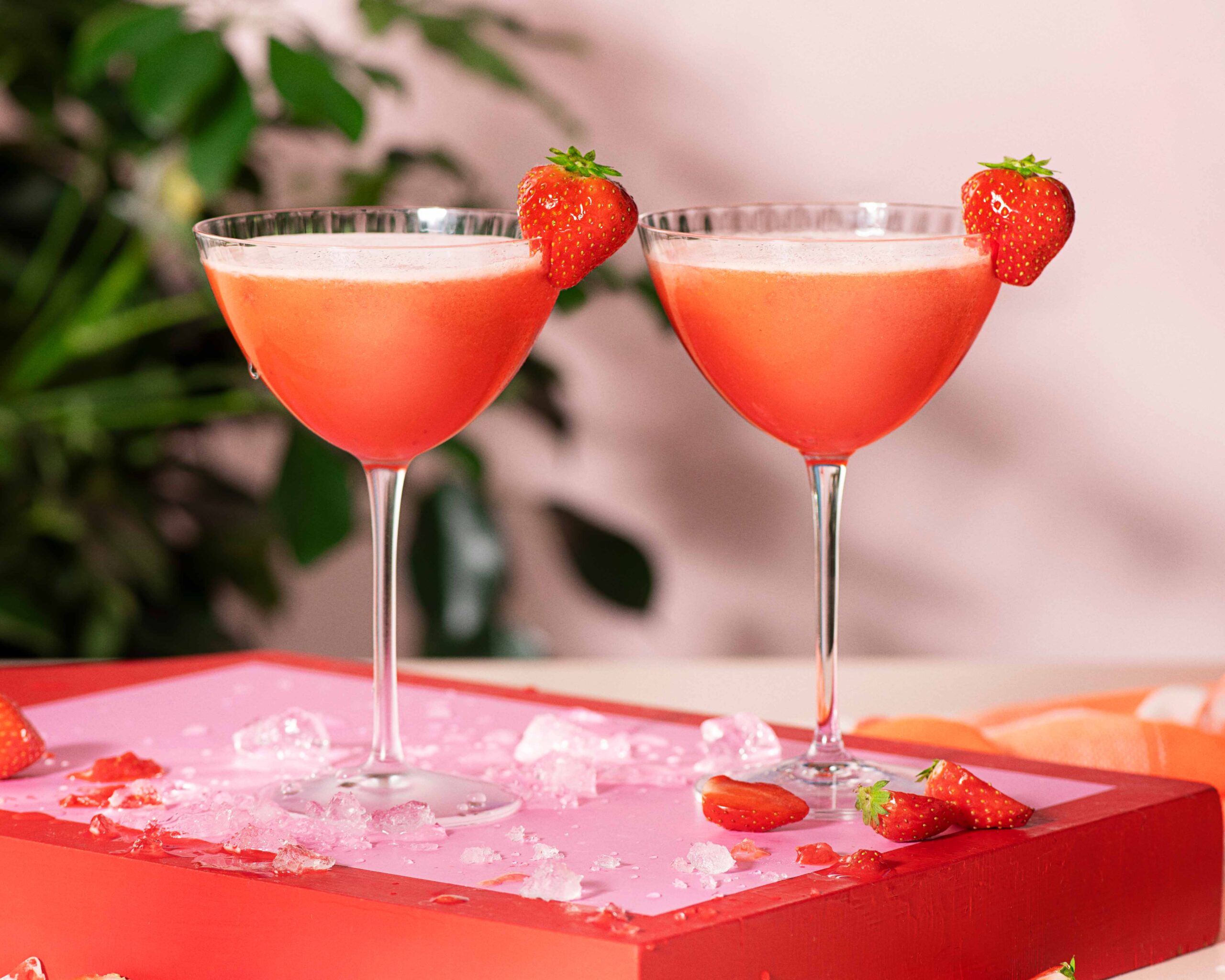 Two Strawberry Daiquiris with strawberry garnish, on a red serving tray