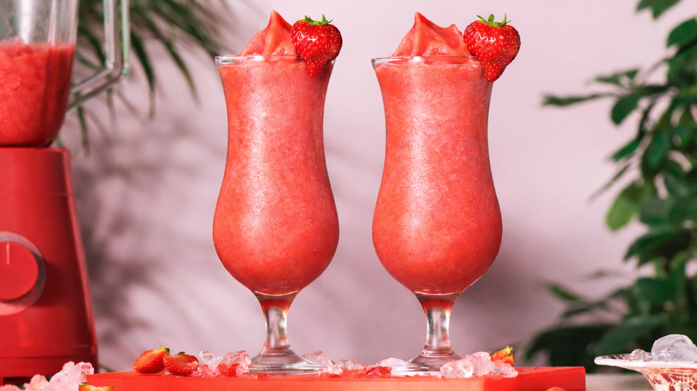 Two red strawberry coladas on a red serving tray
